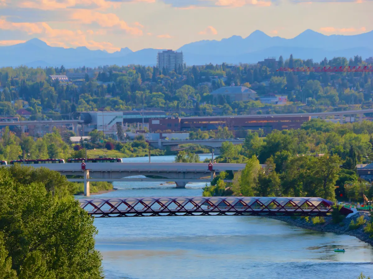 The Peace Bridge crossing the Bow River with Calgary and the Rocky Mountains beyond.