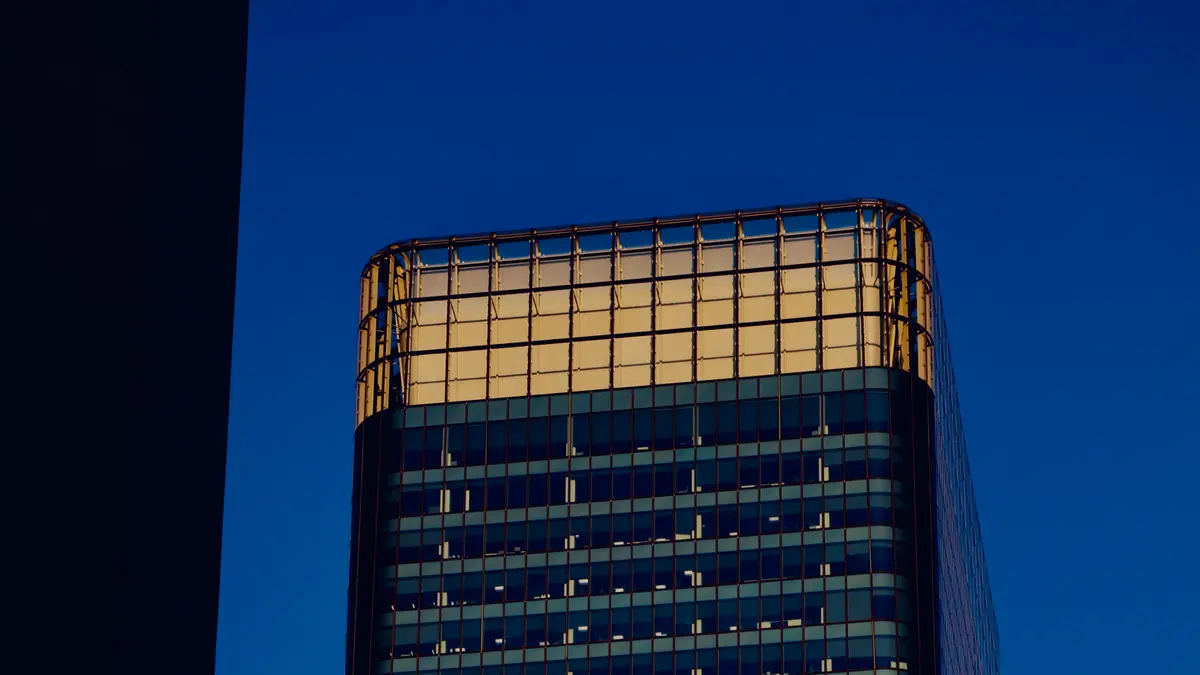 Illuminated crown of a downtown Calgary tower against a deep blue evening sky.