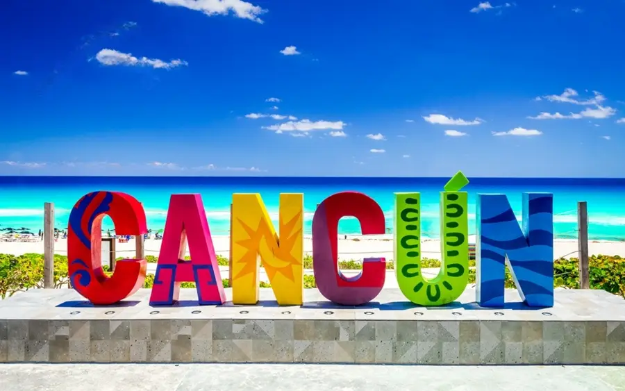Colourful Cancún destination sign beside the Caribbean Sea.