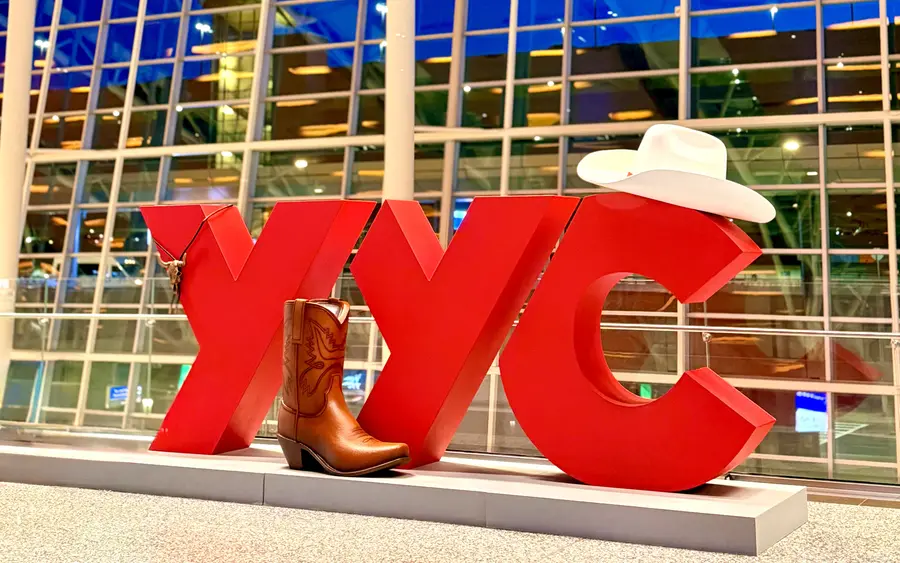 Red YYC airport sign decorated with a white cowboy hat and boot.